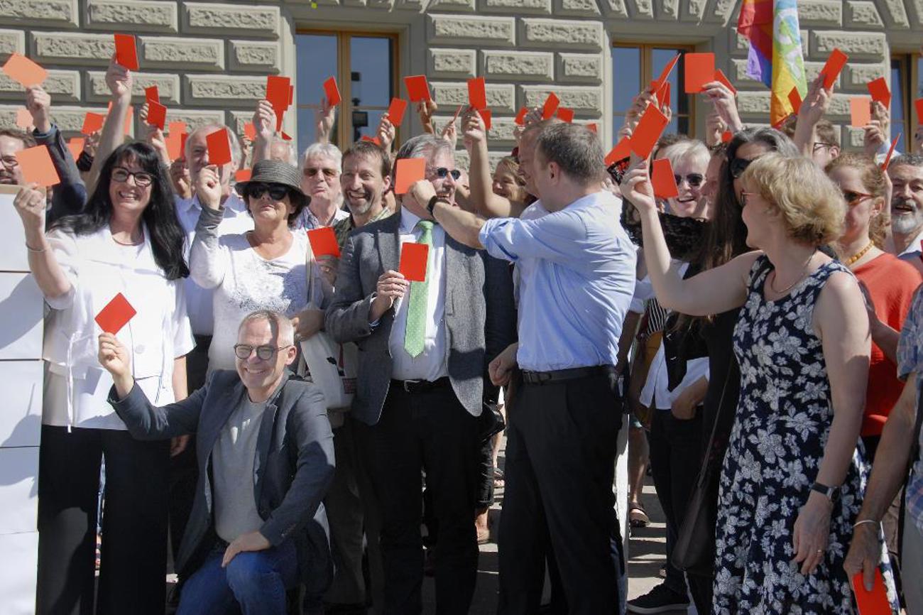 Für die Lockerung der Kriegsmaterialexporte in Bürgerkriegsländer gab es im Juni 2019 bei der Einreichung der «Korrektur-Initiative» die rote Karte – unter anderem von Pfarrer Johannes Bardill (kniend). |Andreas Krummenacher/Pfarrblatt