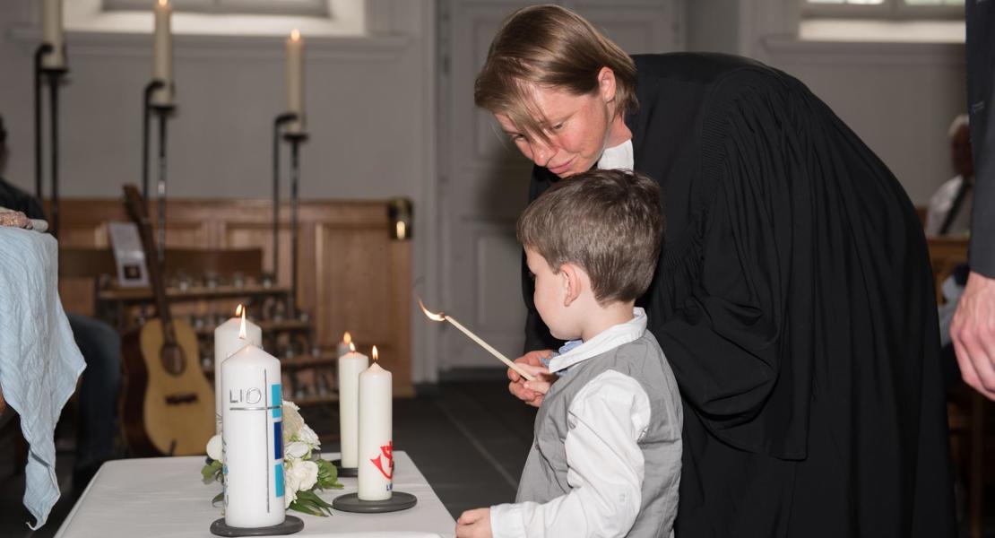 Vielleicht einer der schönsten Momente im Pfarramt: Ein Kind wird getauft, und sein Bruder zündet für es eine Kerze an.
Bild zvg