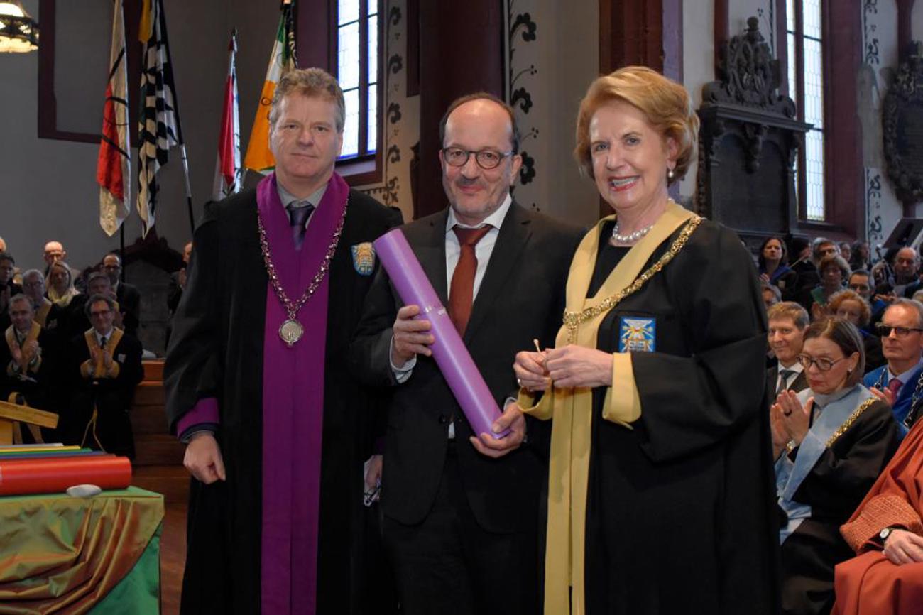 Die Theologische Fakultät der Universität Basel würdigt Pfarrer Martin Stingelin, Kirchenratspräsident Baselland, mit der Verleihung des Ehrendoktortitels durch Dekan Reinhold Bernhardt, rechts: Rektorin Andrea Schenker-Wicki.|Universität Basel/Christian Flierl