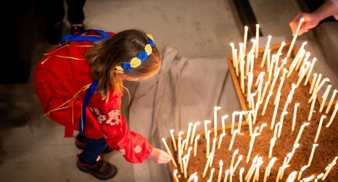 Ein Mädchen aus der Ukraine zündet am ökumenischen Friedensgebet im Berner Münster eine Kerze an.