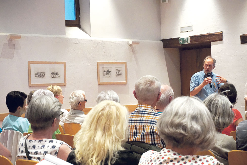 Pfarrer Ulrich Dällenbach steht vor interessierten Zuhörern. Das Publikum ist im Durchschnitt eher älter.