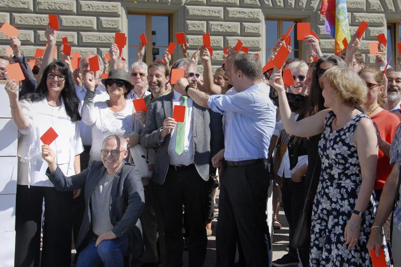 Für die Lockerung der Kriegsmaterialexporte in Bürgerkriegsländer gab es bei der Einreichung der «Korrektur-Initiative» die rote Karte – unter anderem von Pfarrer Johannes Bardill (kniend).|Andreas Krummenacher/Pfarrblatt