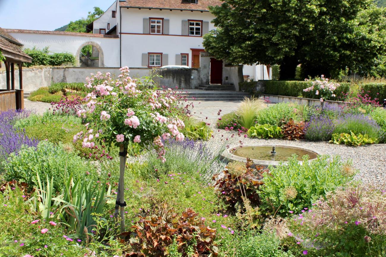 Der Springbrunnen bildet das Zentrum der blühenden Beete.