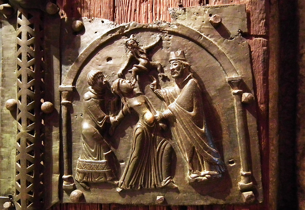 Eine von 23 Tafel aus der Bronzetür der Basilika San Zeno in Verona zeigt den heiligen Zeno, welcher der Legende nach der Tochter des Kaisers Gallienus Dämonen ausgetrieben haben soll. Historisch gesehen ist das unmöglich, weil Gallienus im 3. Jahrhundert, Zeno aber im 4. Jahrhundert lebte. | Bild: WikimediaCommons/Mattana