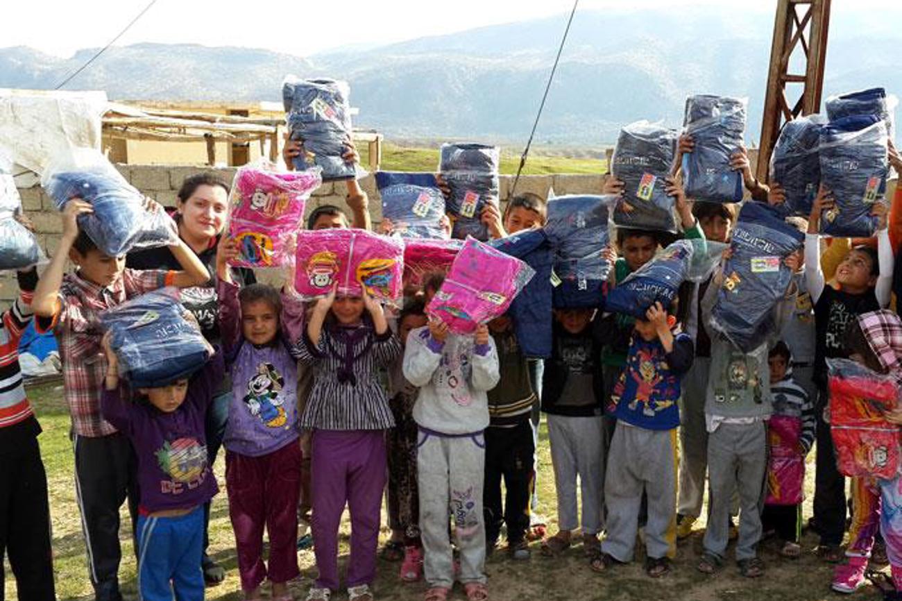 Hilfe für alle, unbesehen ihrer Religion: Kinder freuen sich an einer Lieferung Textilien. | hmk